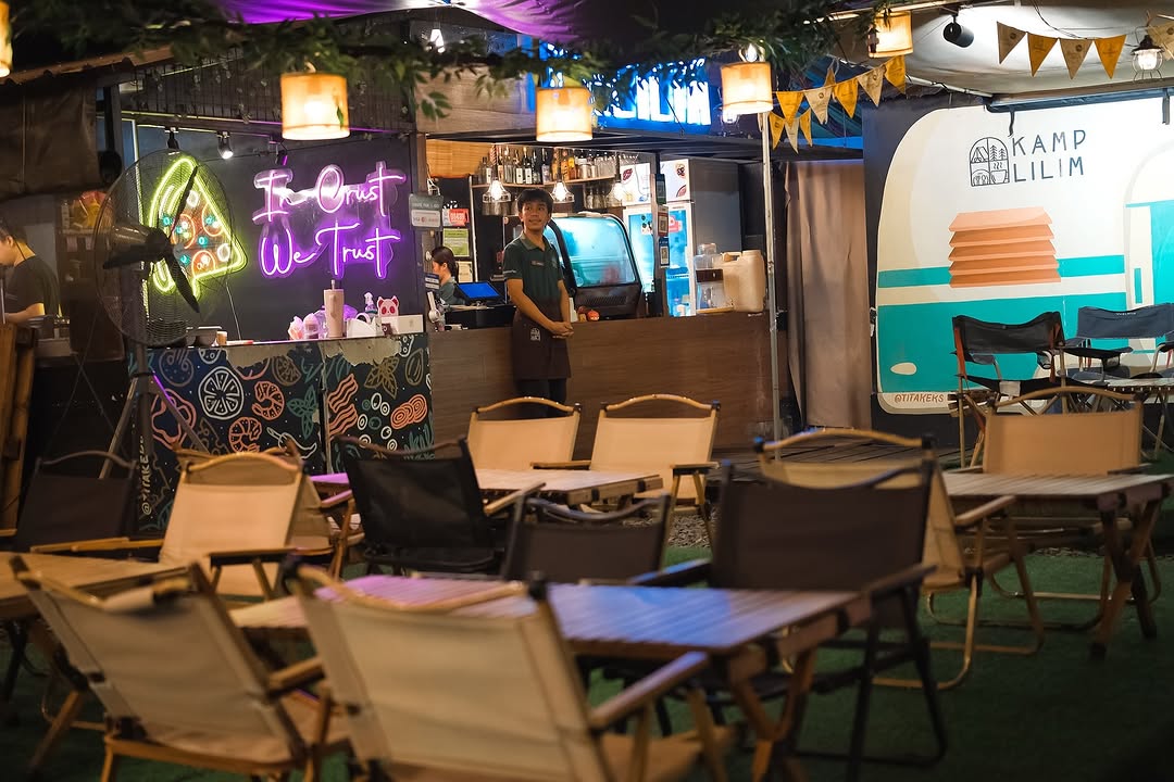 Kamp Lilim bar area with In Crust We Trust neon sign and the vintage caravan