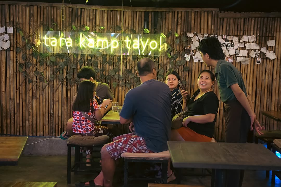 Guests posing at the tara kamp tayo neon sign at Kamp Lilim